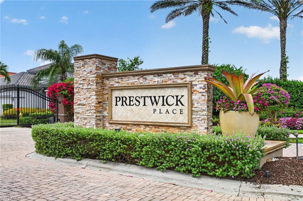 Stone-clad entry monument with "Prestwick Place" signage, flanked by manicured hedges and a large decorative planter and monitored iron gates