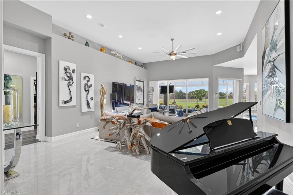 Spacious living area featuring polished porcelain tile flooring, high ceilings with recessed lighting, and a contemporary ceiling fan