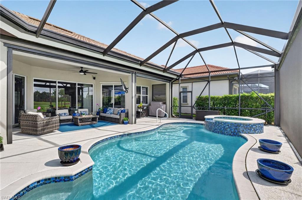 Screened lanai featuring the large covered outdoor living/entertainment area, a freeform pool with integrated spa and mosaic tile accents