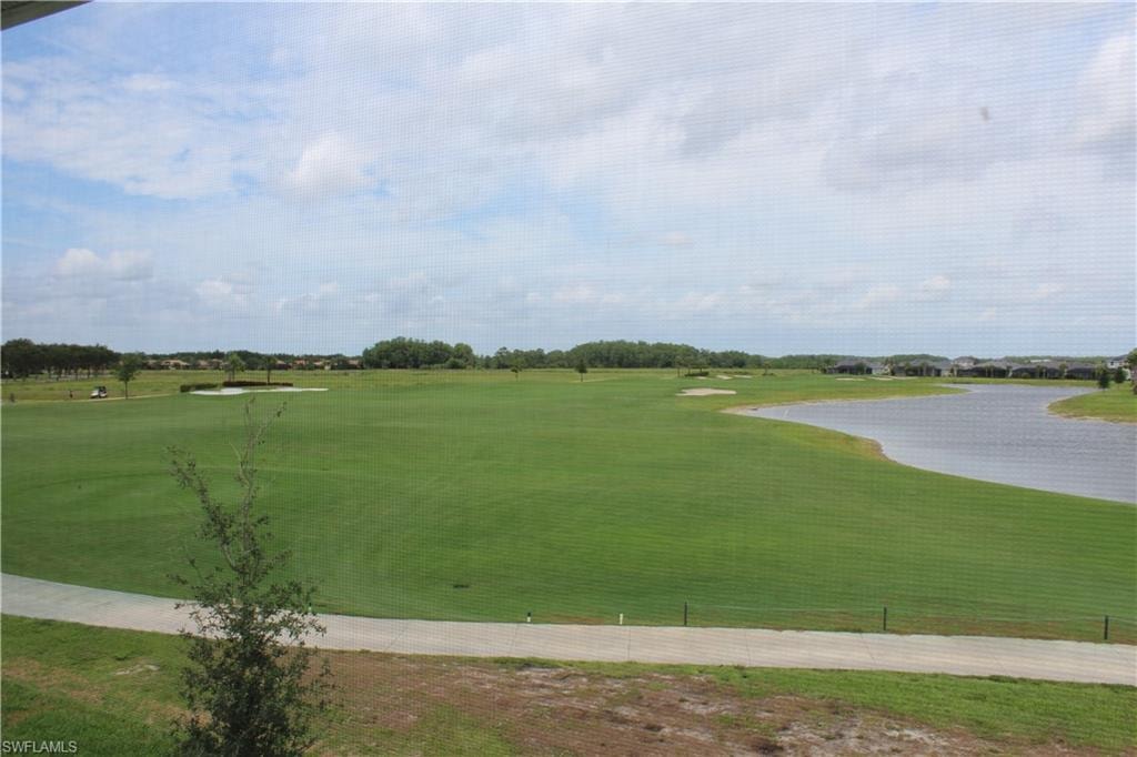 View of property's community with golf course view, a yard, and a water view