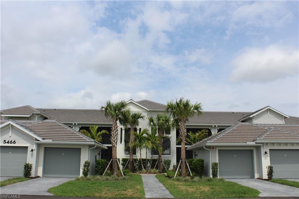 View of front of house with a tile roof, stucco siding, driveway, and an attached garage
