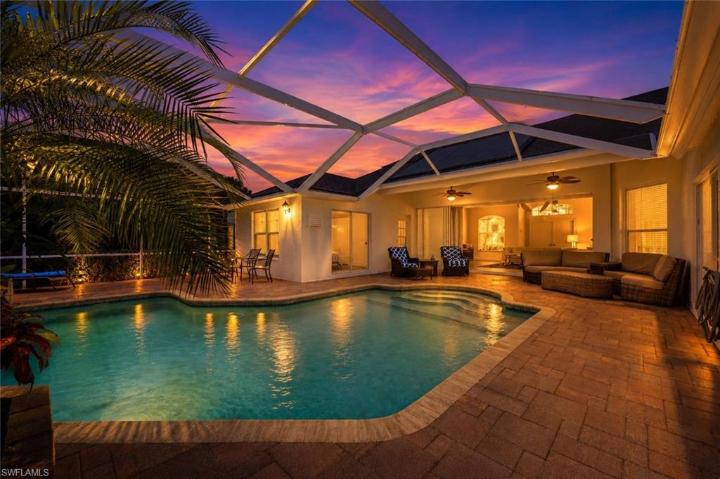 Screened lanai featuring a swimming pool, integrated spa, and brick paver decking
