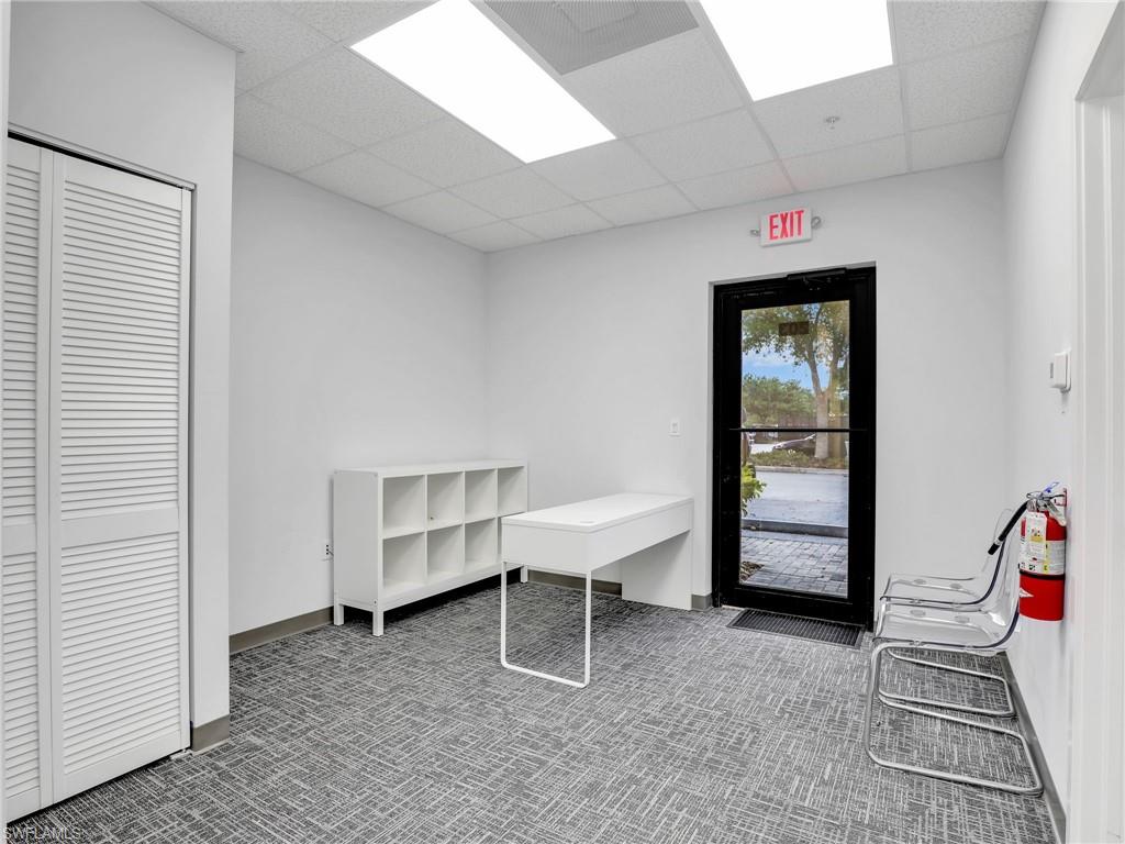 Entrance area featuring a full-light glass door, louvered bi-fold closet doors, and patterned carpet flooring