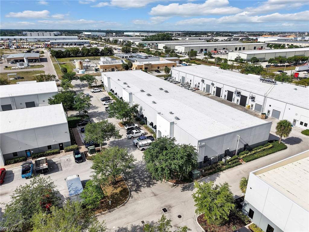 Industrial park featuring multiple single-story commercial buildings, expansive paved parking areas, and mature landscaping