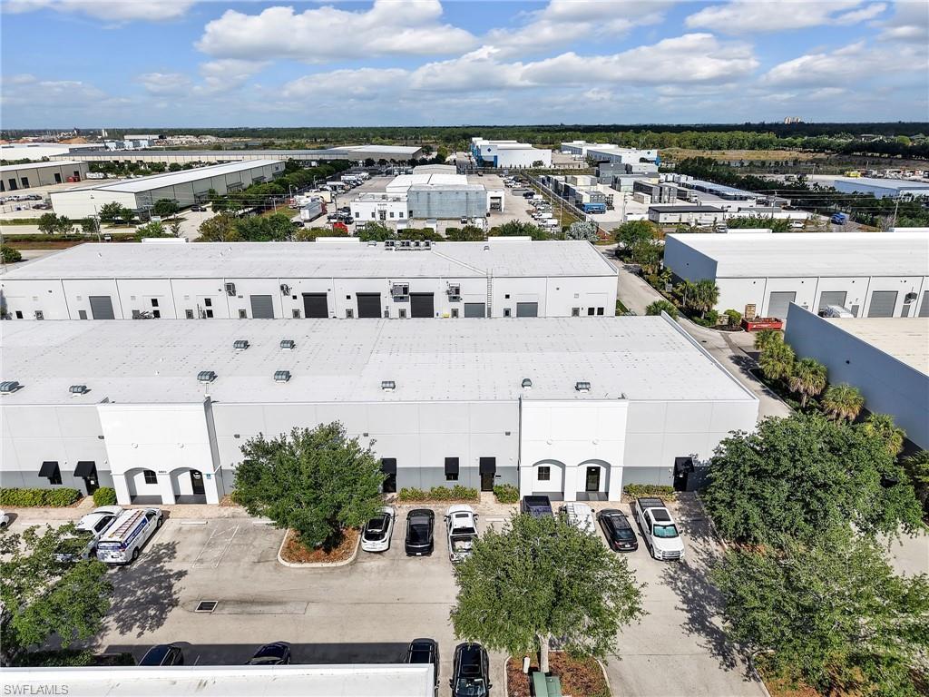 Industrial building featuring multiple garage bays, a paved parking lot, and mature landscaping