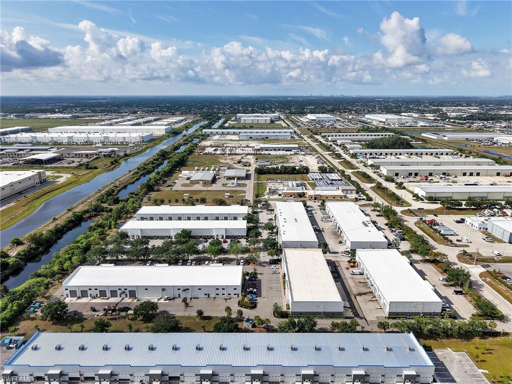 Expansive industrial park featuring multiple white-roofed buildings, a prominent waterway, extensive paved areas, and mature landscaping