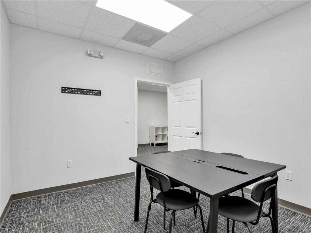 Commercial space featuring light gray walls, patterned carpet flooring, and a white paneled door