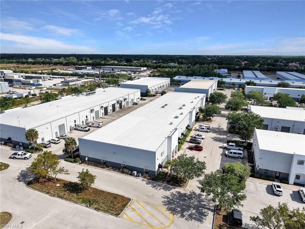 Industrial park featuring multiple single-story commercial buildings, expansive paved parking areas, and mature landscaping