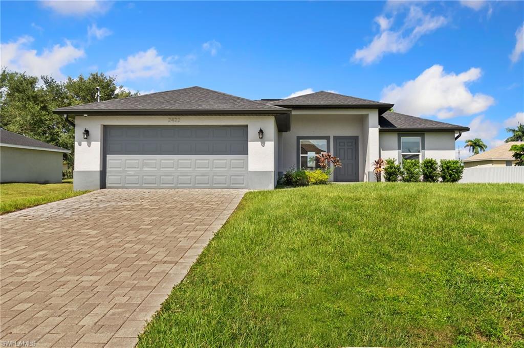 Contemporary single-story residence with a two-tone exterior finish, a dark shingle roof, and a paver driveway