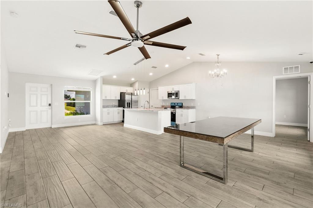 Open-concept living area featuring wood-finish tile flooring, vaulted ceilings, and a contemporary ceiling fan
