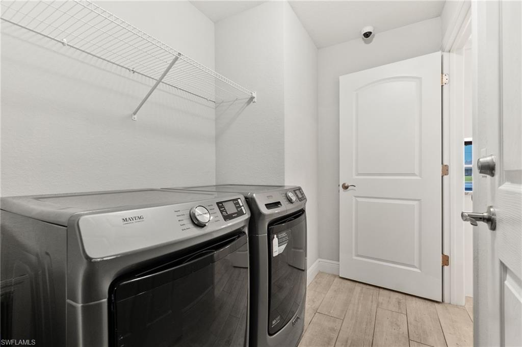 Dedicated laundry area featuring wood-finish flooring, light gray walls, and a white wire shelving unit for storage