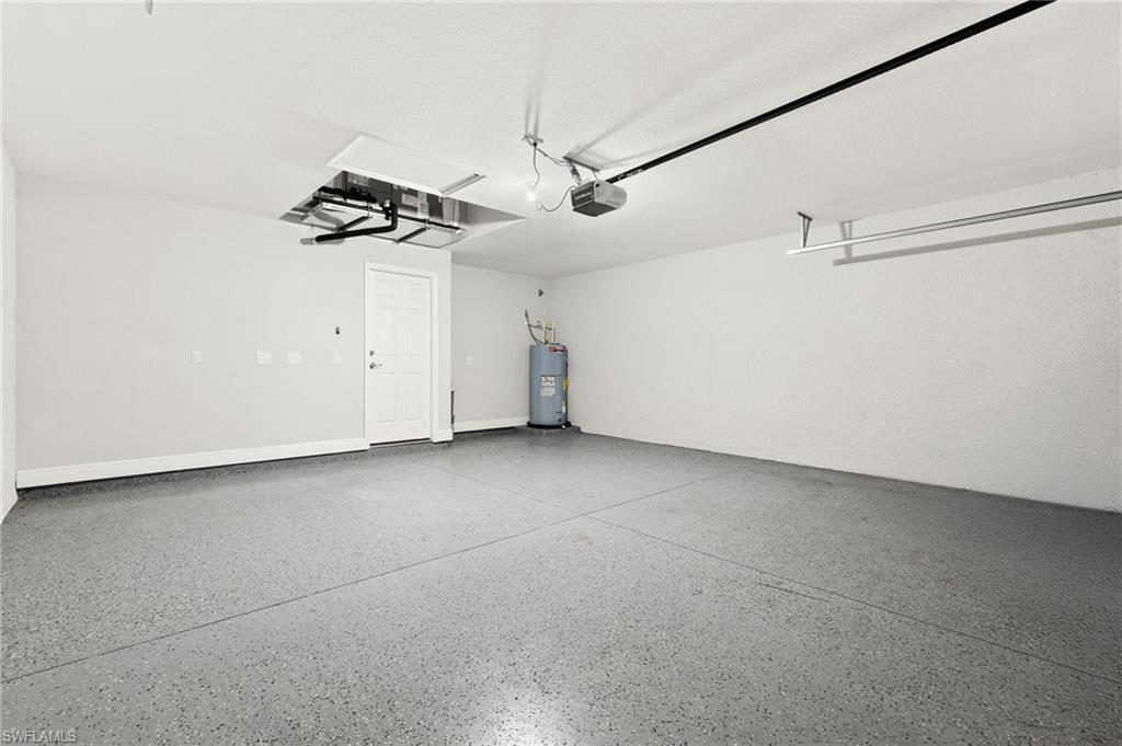 Spacious garage featuring epoxy flooring, a paneled interior door, and a built-in overhead storage rack