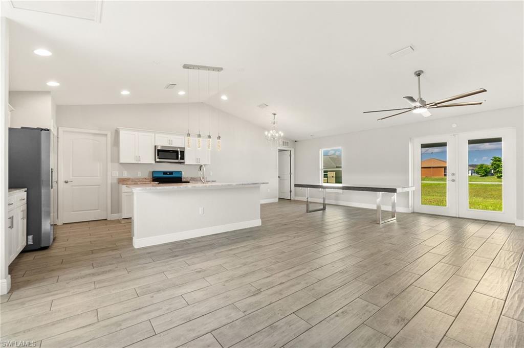 Open-concept interior featuring light wood-look tile flooring, vaulted ceiling, and recessed lighting