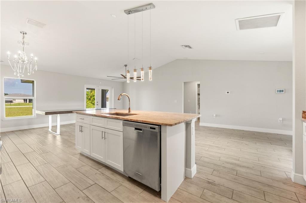 Open-concept living space featuring a central kitchen island with a built-in sink and stainless steel dishwasher