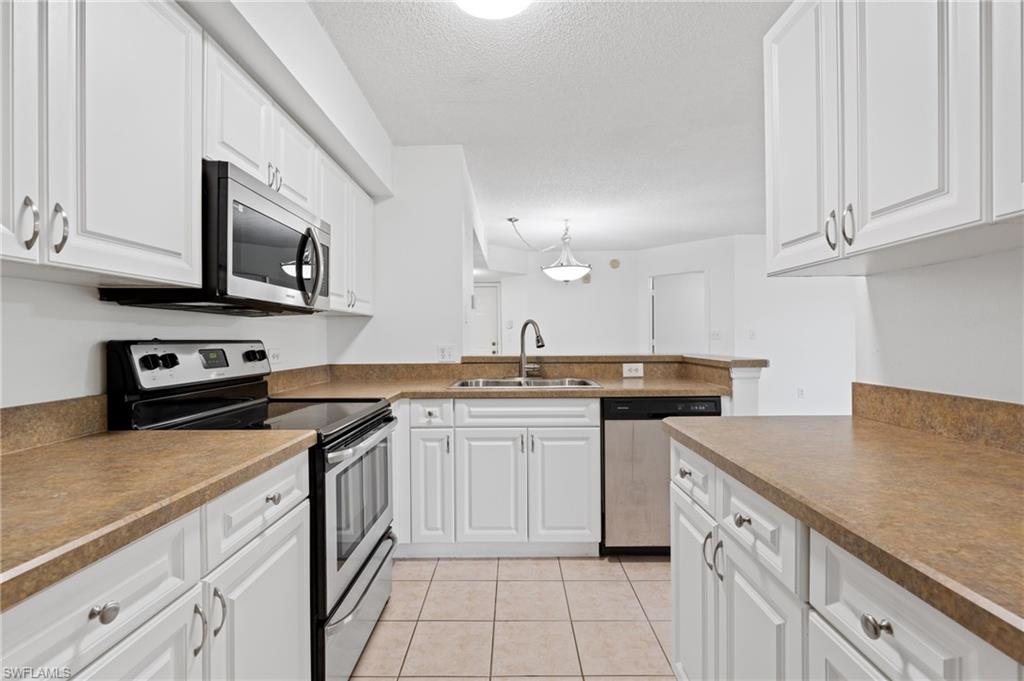 Kitchen featuring hanging light fixtures, white cabinetry, appliances with stainless steel finishes, and a sink