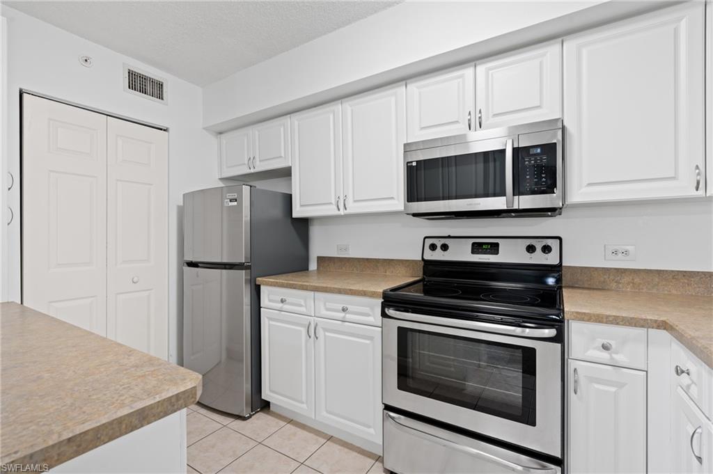 Kitchen with light tile patterned floors, visible vents, white cabinetry, light countertops, and appliances with stainless steel finishes
