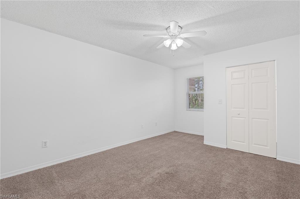 Unfurnished bedroom featuring a closet, a ceiling fan, carpet flooring, a textured ceiling, and baseboards
