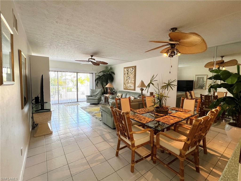 Open-concept living and dining areas featuring tile flooring, ceiling fans, and a sliding glass door