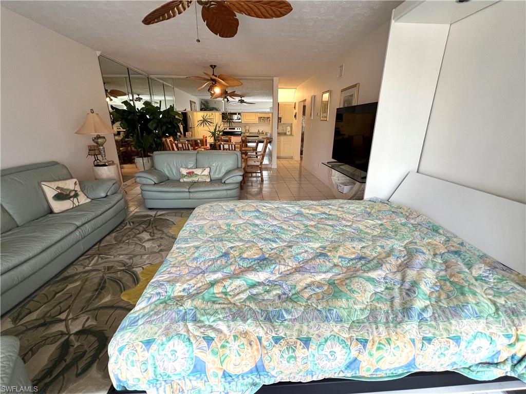 Spacious living area featuring a custom wall bed, decorative ceiling fans, and a mirrored accent wall