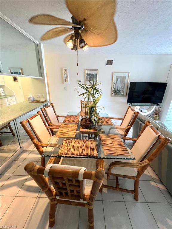 Dining area featuring tile flooring, a ceiling fan with integrated lighting, and a mirrored wall accent