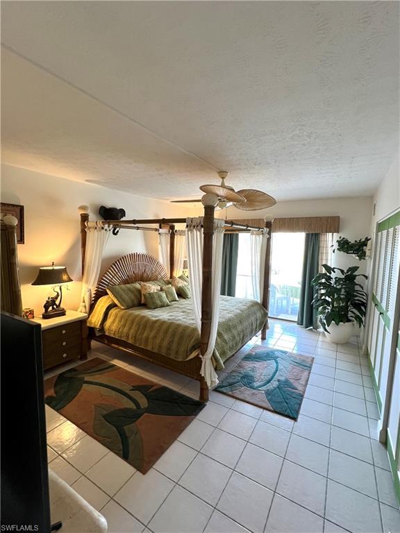 Spacious bedroom featuring convenient tile flooring and a ceiling fan, two slider closets and an armoire