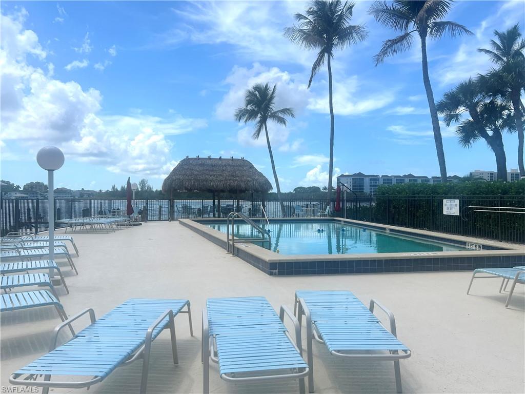 Swimming pool area featuring a thatched  hut, palm trees, and a surrounding pool deck