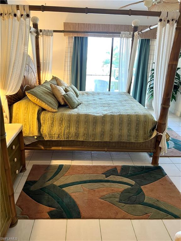 Four-poster bed with canopy drapes, wicker headboard, and a bamboo-look nightstand