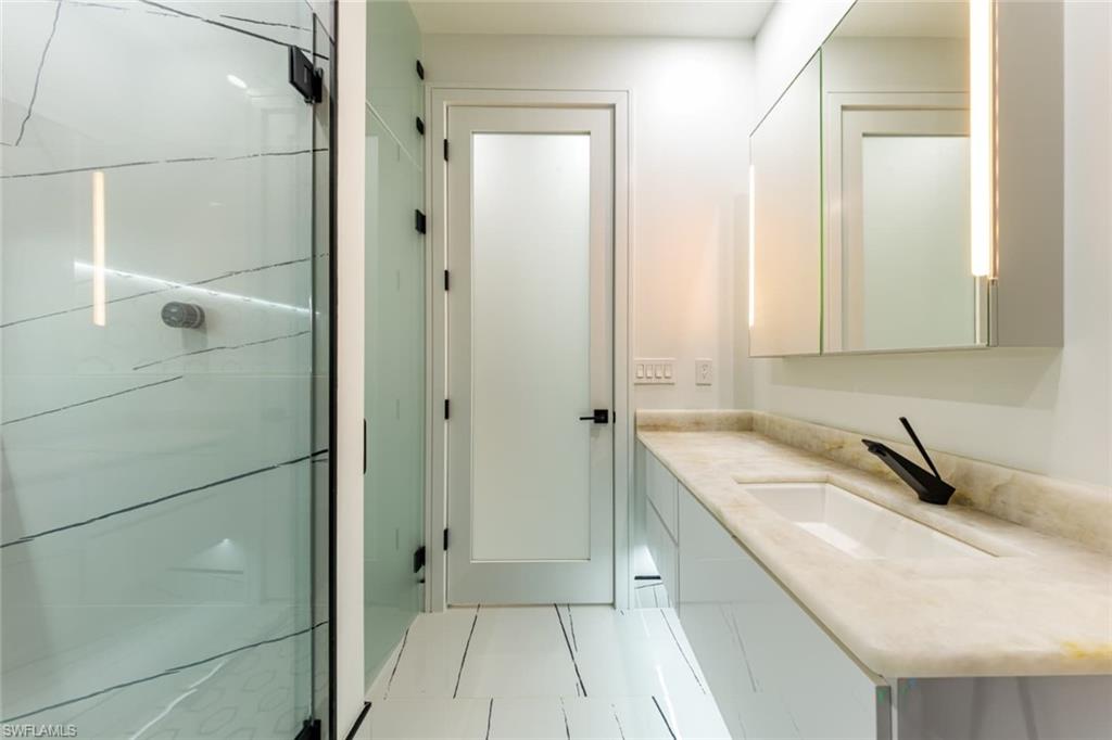 Full bathroom featuring vanity, light tile patterned flooring, and a shower stall