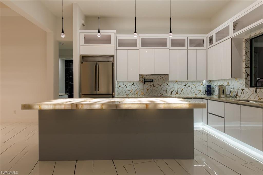 Kitchen with pendant lighting, wood counters, tasteful backsplash, and white cabinets
