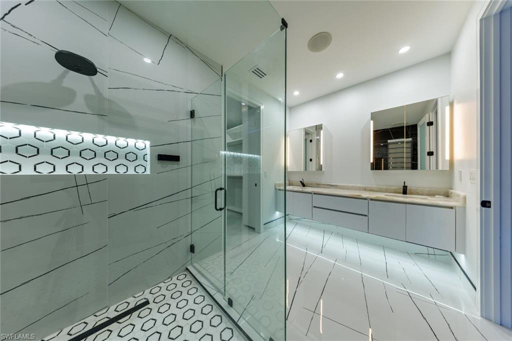 Full bathroom featuring double vanity, a stall shower, light tile patterned floors, and recessed lighting