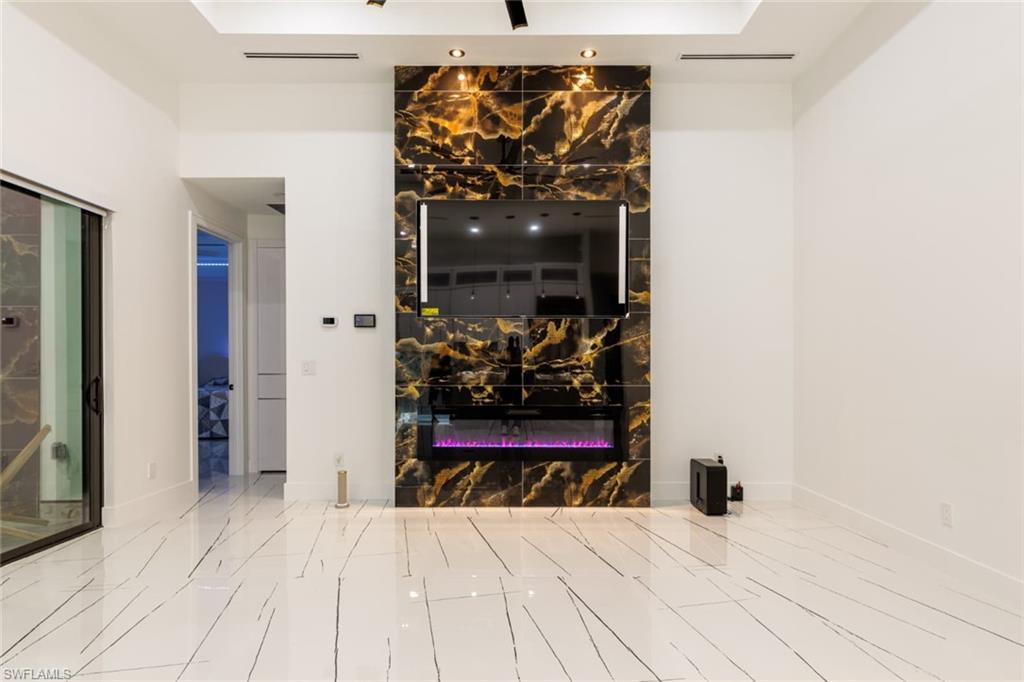 Unfurnished living room featuring a glass covered fireplace