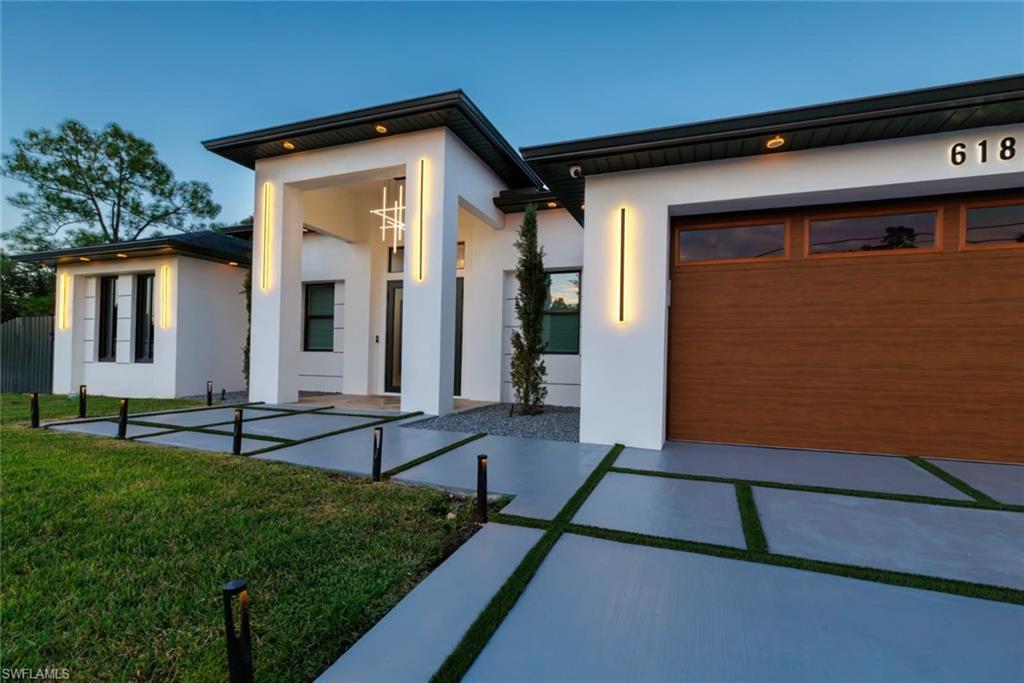 Modern home featuring stucco siding, a front yard, a concrete driveway and a garage