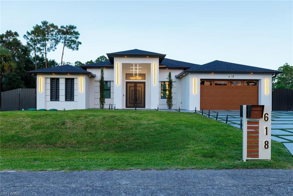 View of front of home with stucco siding, driveway, an attached garage, and roof with shingles