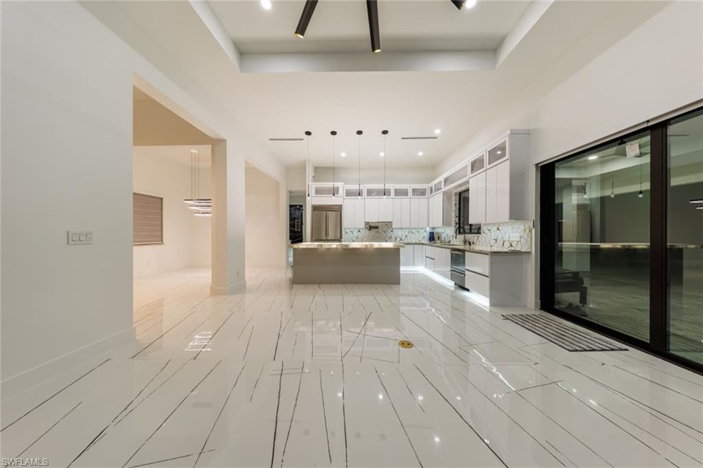 Living Room/Kitchen area with a center island, decorative backsplash, glass insert cabinets, decorative light fixtures, and modern cabinets