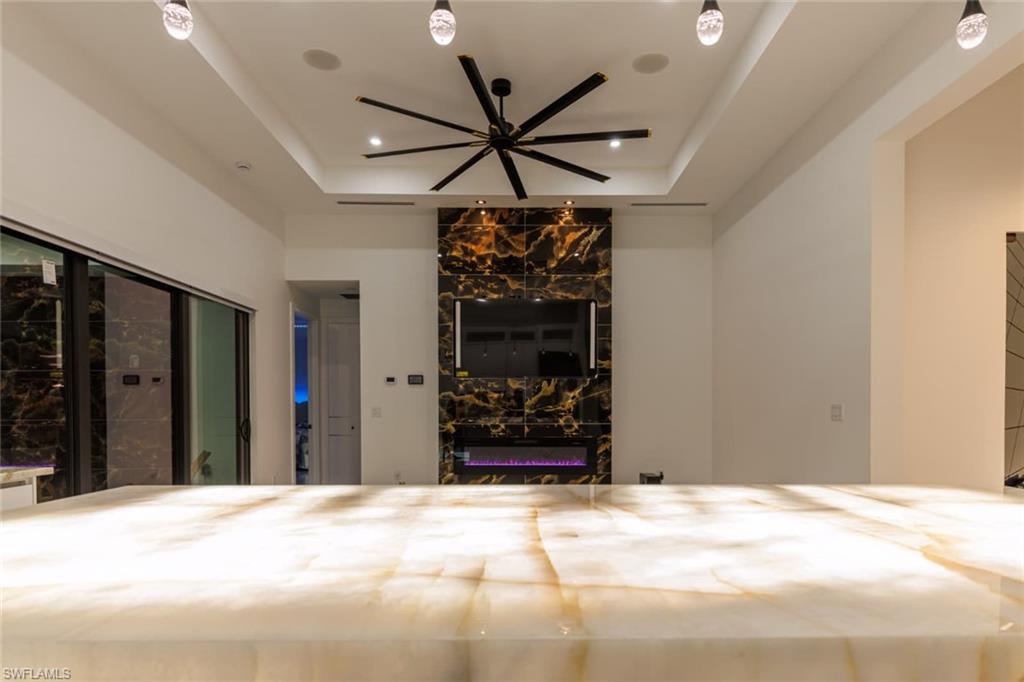 Unfurnished bedroom featuring access to outside, a premium fireplace, and a raised ceiling