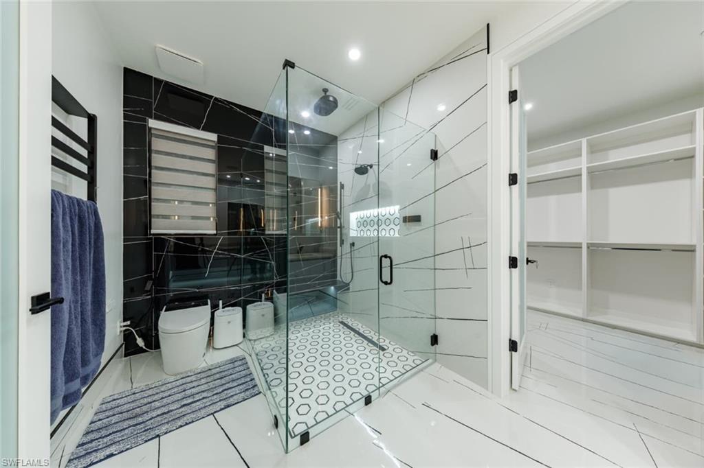 Master Bathroom with tile patterned floors, a stall shower, tile walls, and a spacious closet