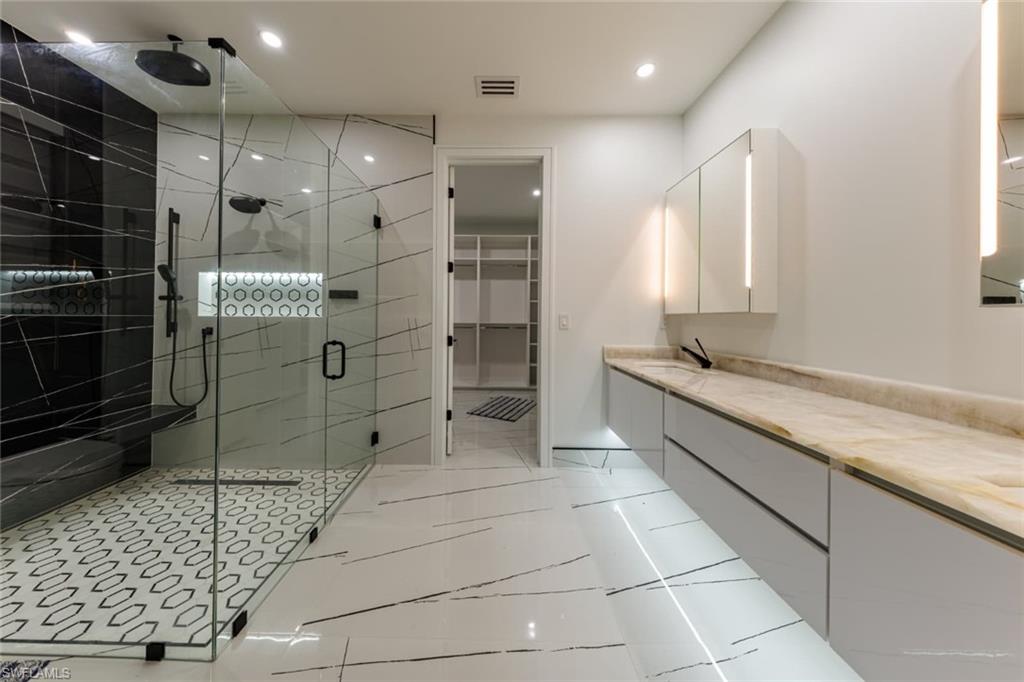Master Bathroom with double vanity, a shower stall, a spacious closet, light tile patterned floors, and recessed lighting