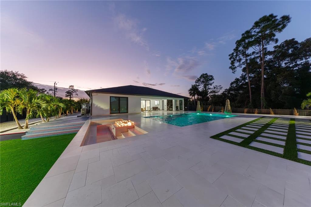 Pool at dusk with a patio and a fire pit