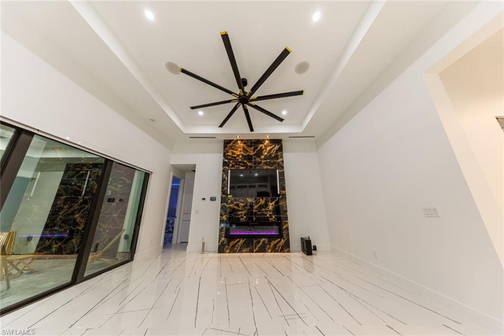 Unfurnished living room with a raised ceiling and ceiling fan