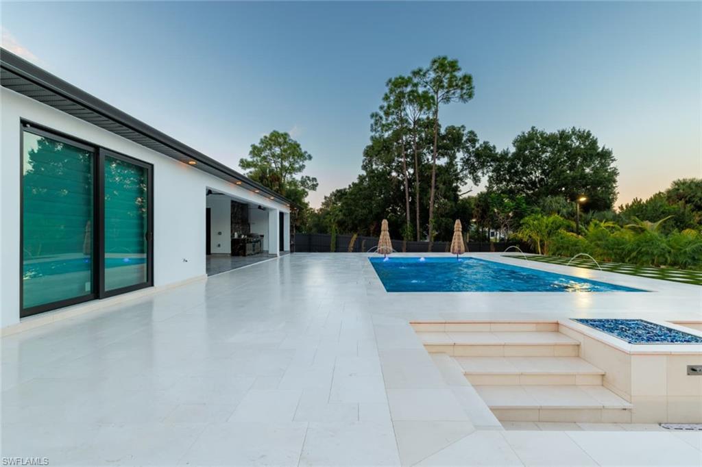 Pool at dusk featuring a patio and a fire pit