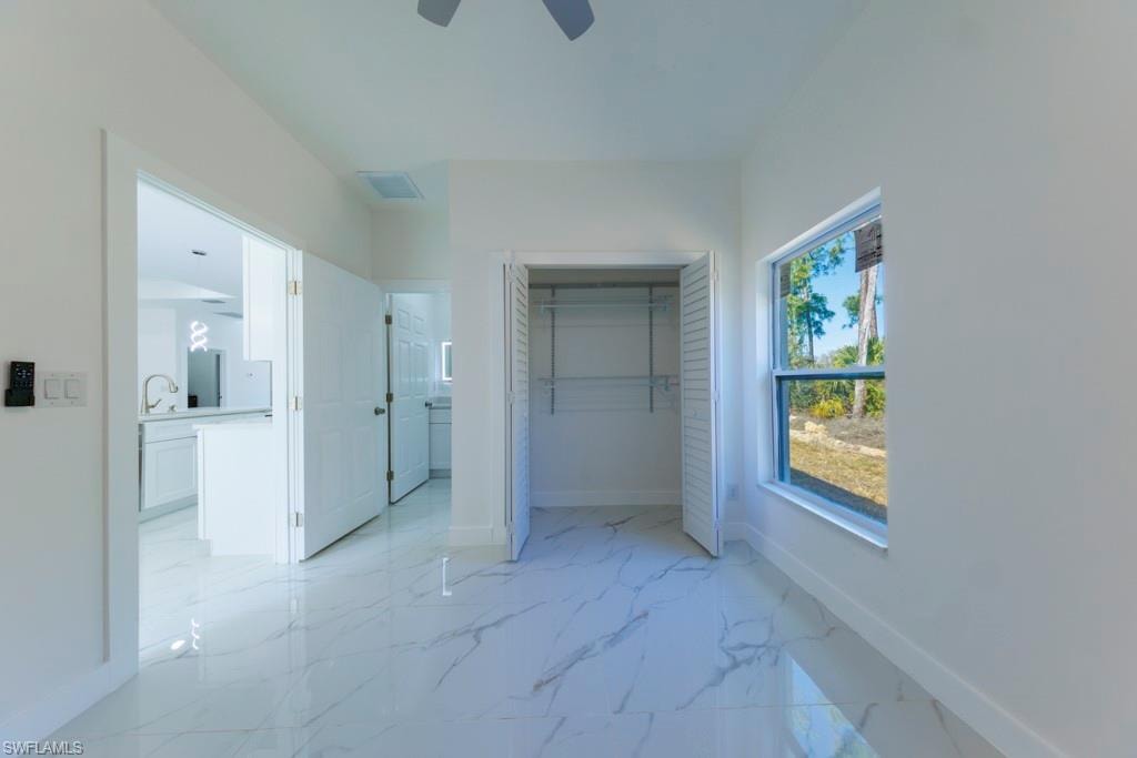 Spacious room featuring white walls and marble-look tile flooring