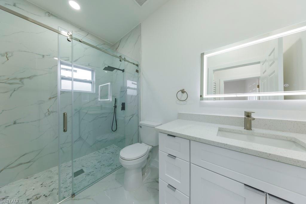 Contemporary bathroom featuring a spacious glass-enclosed shower with large format tile, a modern vanity with integrated sink and stone-finish countertop, and an illuminated mirror