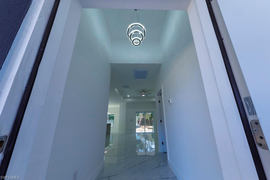 Entryway featuring a modern tiered chandelier, high ceilings, recessed lighting, and large format marble-look flooring