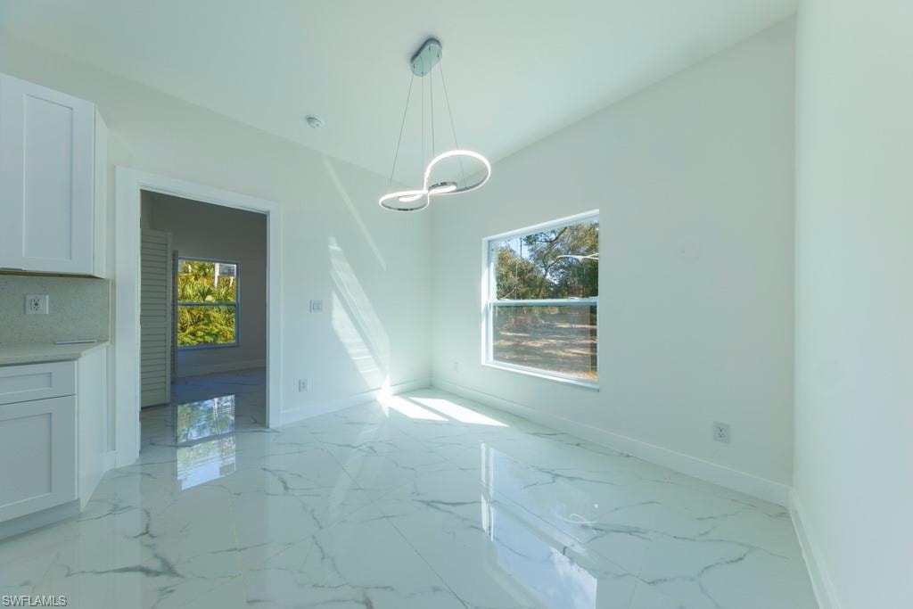 Spacious room featuring large format tile flooring, a modern linear chandelier, and a bright window with exterior landscaping