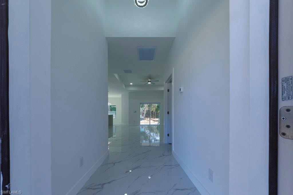 Entryway featuring large format white tile flooring with gray veining, white walls, and recessed lighting