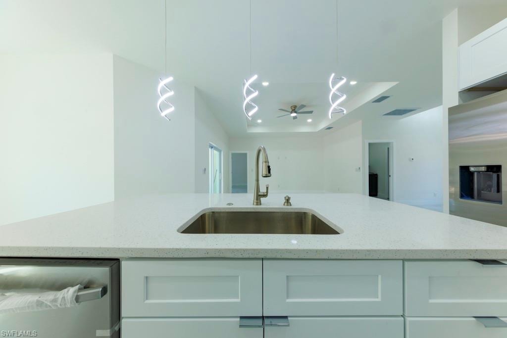 Kitchen island featuring a stainless steel sink with a high-arc faucet, light-toned countertop, and white shaker-style cabinetry with rectangular hardware