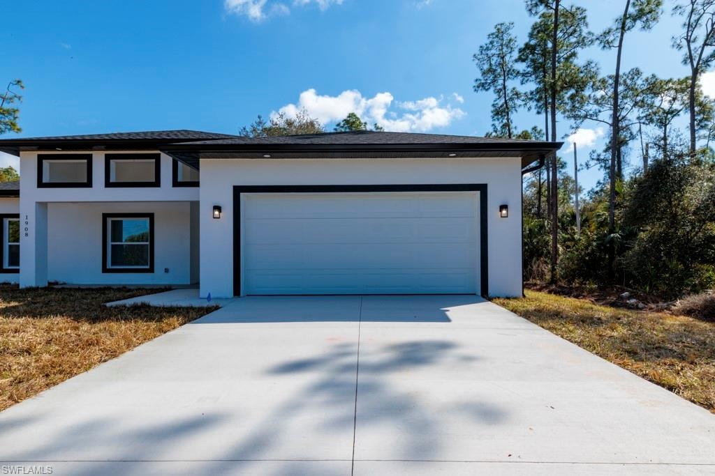 Modern exterior featuring a two-car garage with black trim, a concrete driveway, and recessed outdoor lighting