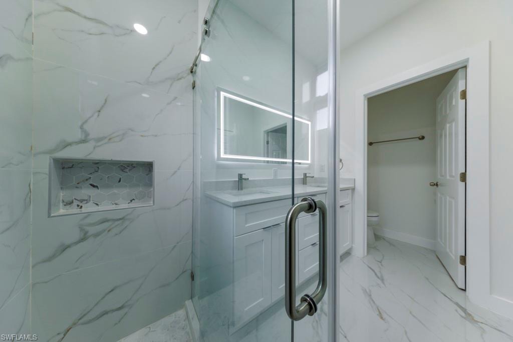 Glass-enclosed shower with large format tile walls and a hexagonal tile niche