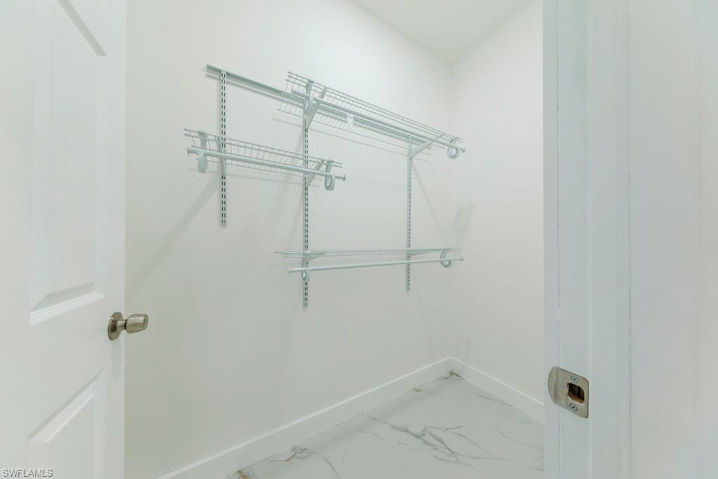White interior space featuring adjustable wire shelving systems, white baseboards, and light-colored flooring with subtle veining