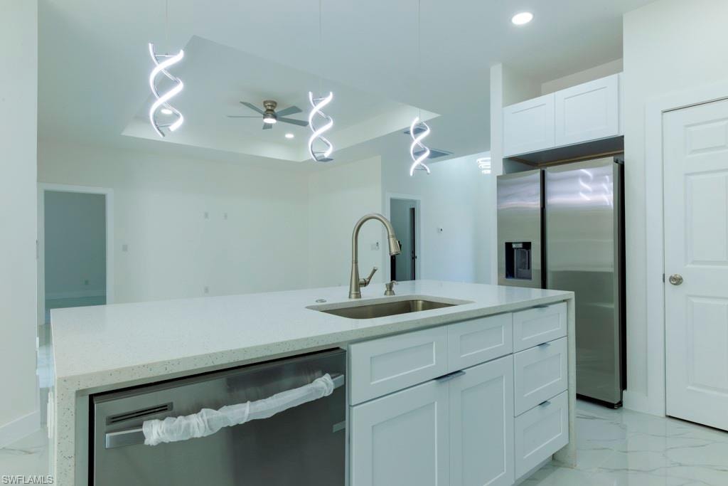 Kitchen island featuring a stainless steel sink, contemporary faucet, and white shaker-style cabinetry